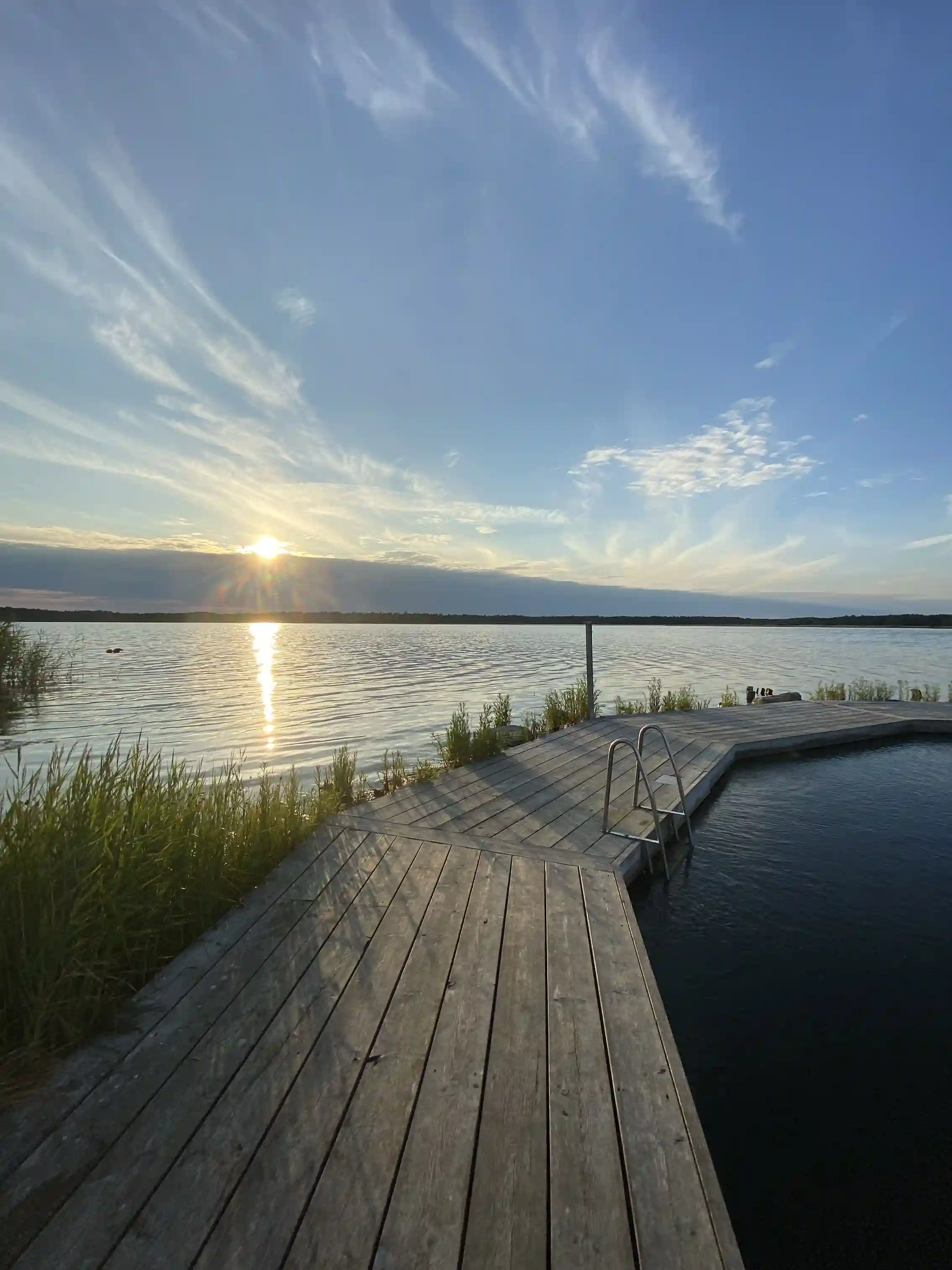 En brygga som sträcker sig ut över en blå sjö vid horisonten vid Fide Äventyrsby & Camping.