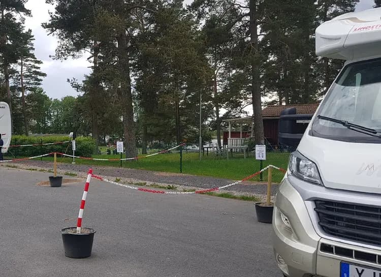 En husbil parkerad på Hjortsjöns camping, omgiven av grönska och andra parkerade bilar.