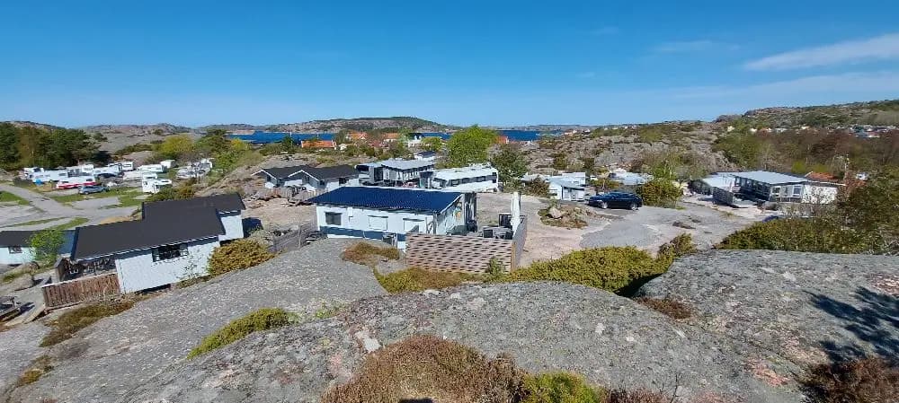 En panoramautsikt över Fjällbacka Camping som visar ett naturskönt landskap med sluttande berg, by och klippformationer i bakgrunden.