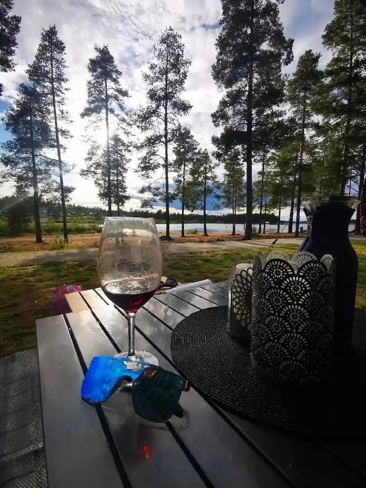 En utomhusbar vid Bovikens havsbad med olika glas och flaskor på bordet, solsken och skugga över möblerna.