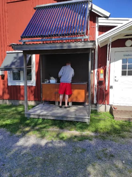 Bild av Sangis Motell och Camping. En utomhusstruktur med en markis som ger skugga. Byggnadens sidopaneler syns tydligt.