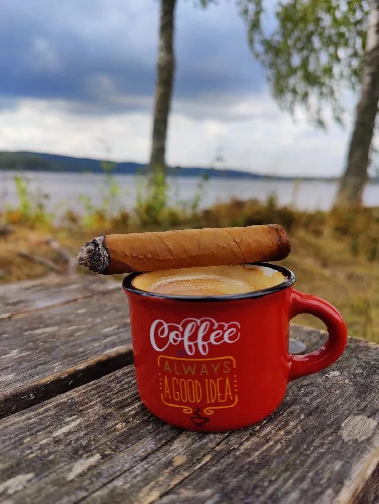 En kaffemugg och en tobaksprodukt på ett träbord vid Säter camping.
