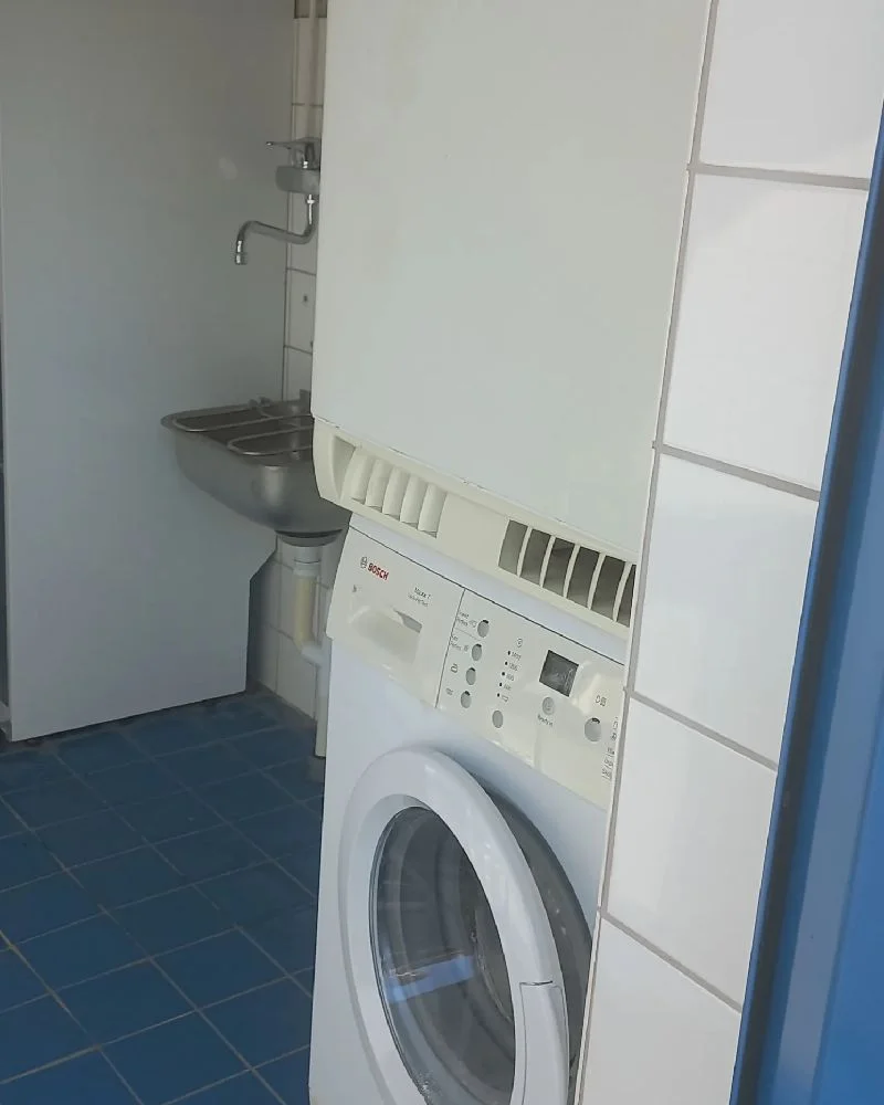 En tvättstuga med tvättmaskin och torktumlare mot en kaklad vägg på allégården kastlösa.