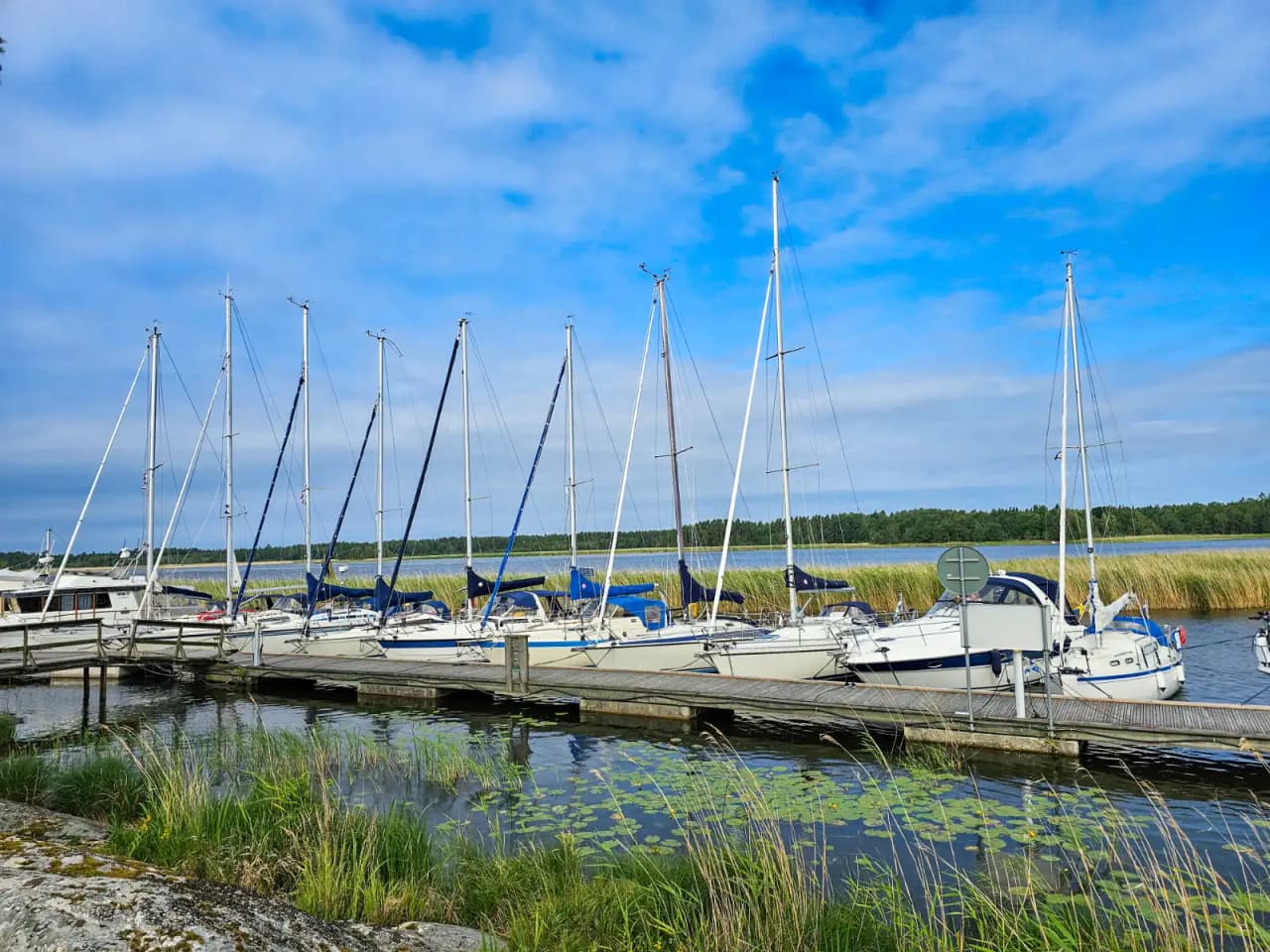Bild av Ekenäs gästhamn och camping: flera båtar ligger förtöjda i den blå hamnen, omgivna av bryggor och master, med en vy över en livlig marina.