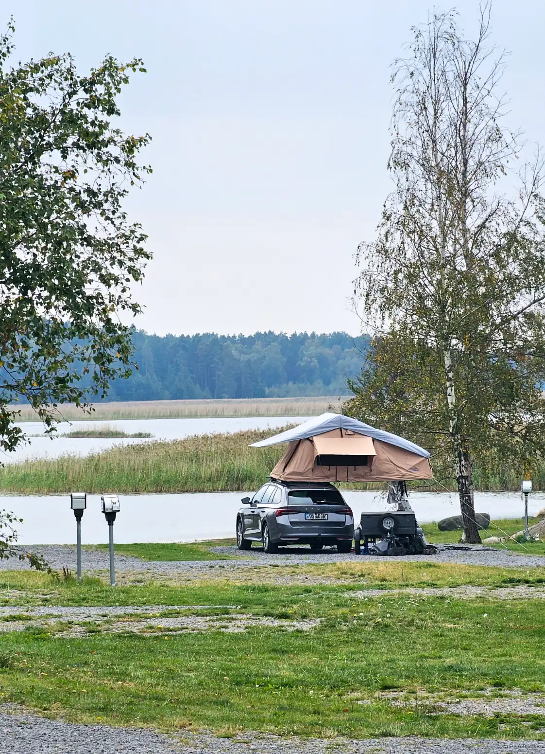 En bild av en parkeringsplats vid Ekenäs gästhamn & camping, där flera bilar av olika storlekar och typer är parkerade.