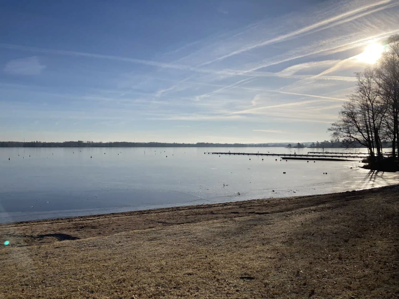Utsikt över Evedals camping med blå himmel och ett stilla vattendrag i förgrunden.