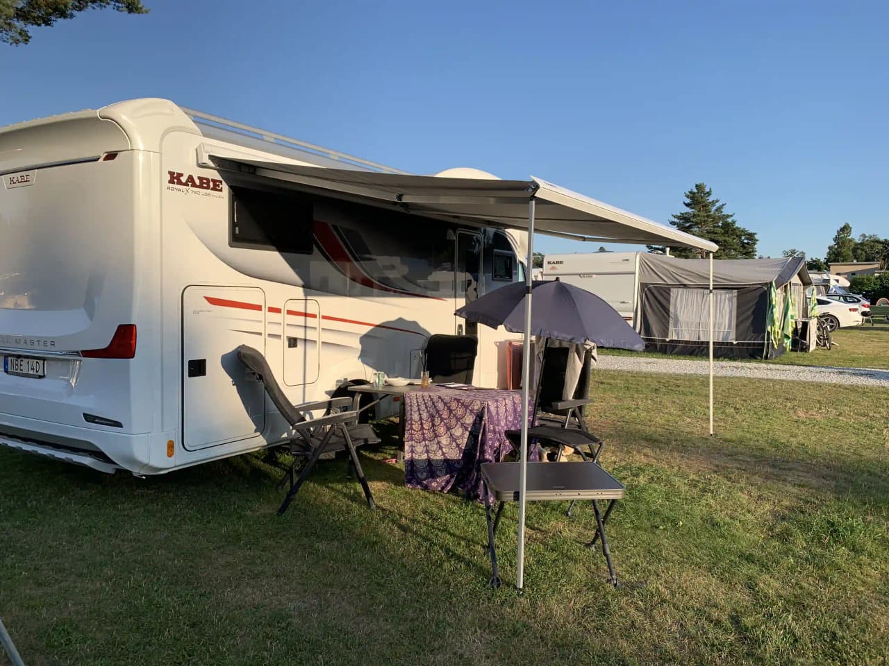 En campingplats vid Sudersand Resort med husvagnar, en skåpbil och flera tält under tak.