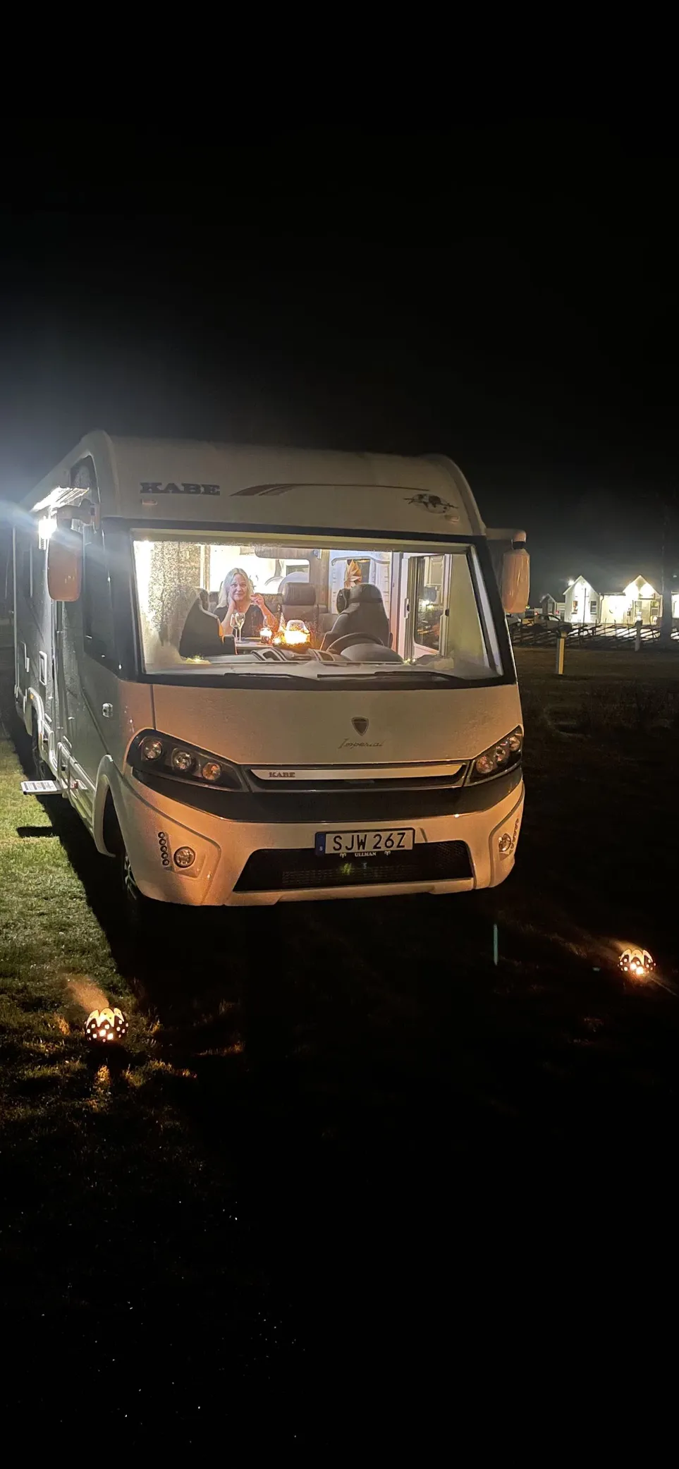 Bild på en husbil parkerad på Sudersand Resort under natten. Bilens vindruta och speglar syns tydligt, och den omgivande miljön ger en känsla av camping och avkoppling.