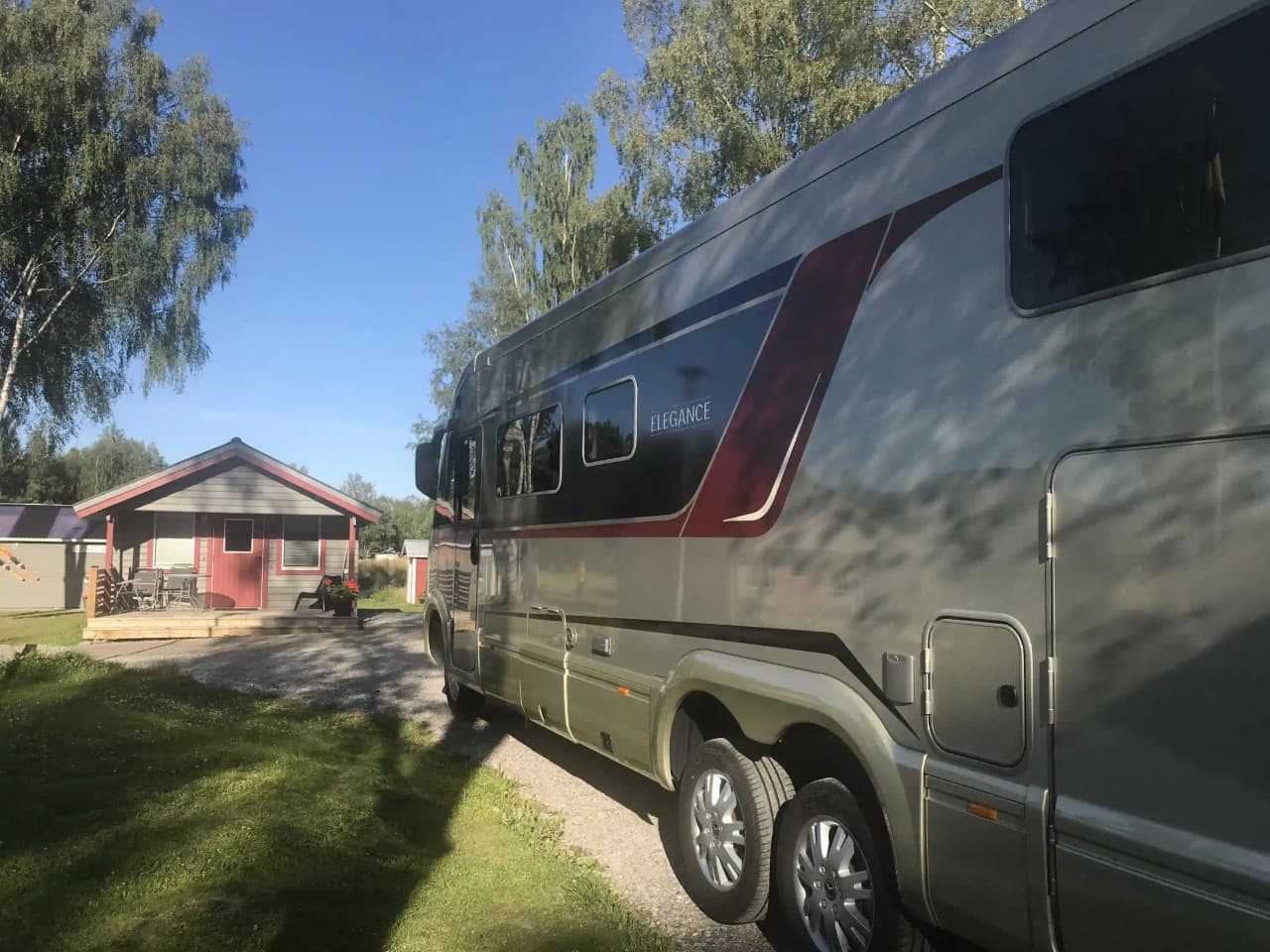 En bild av en husvagn parkerad på Överhörnäs camping, omgiven av grönska under en klarblå himmel.