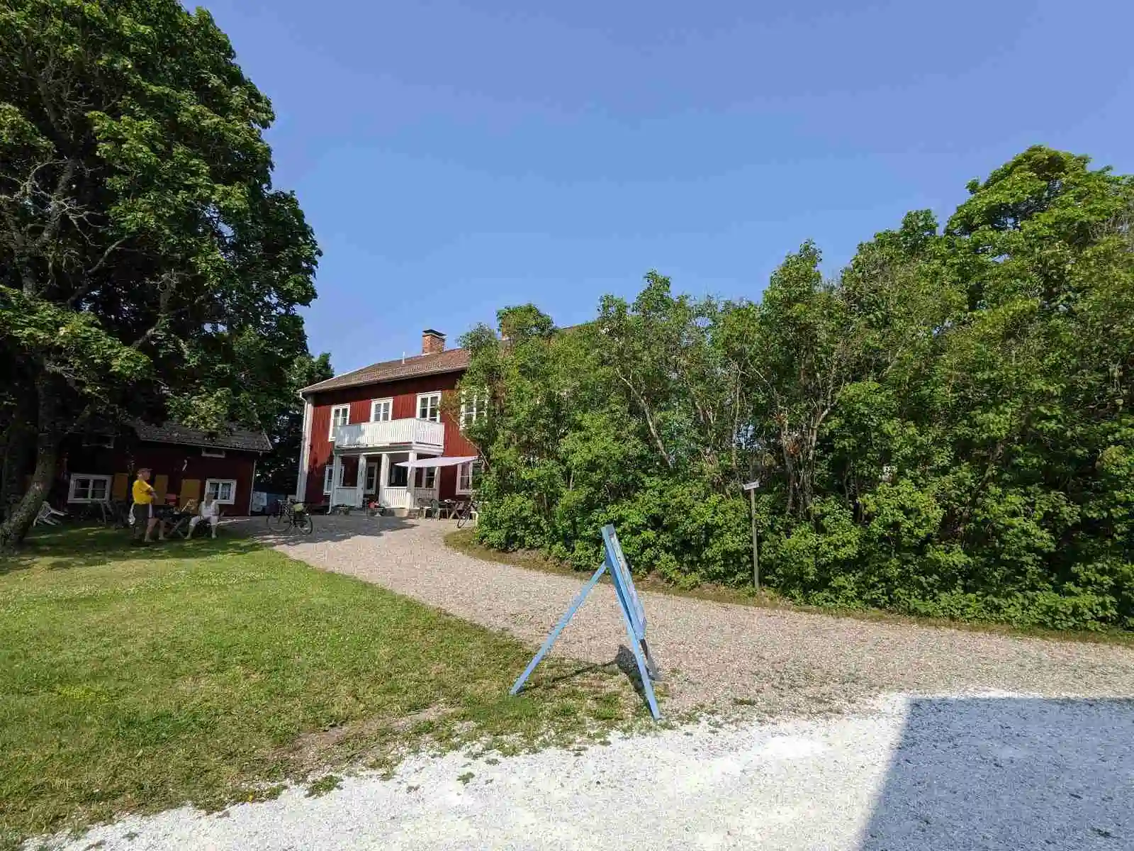 En vit kursgård byggnad med stora fönster och en välskött gräsmatta framför.