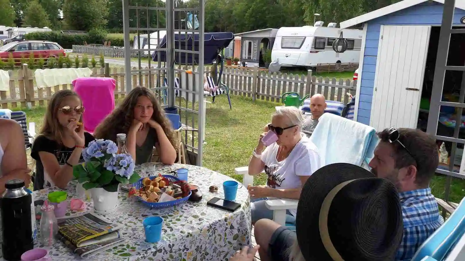 Ett campingområde med ett picknickbord och stolar utomhus. Området ser inbjudande ut för rekreation och samvaro, kanske med mat och nöje i fokus.