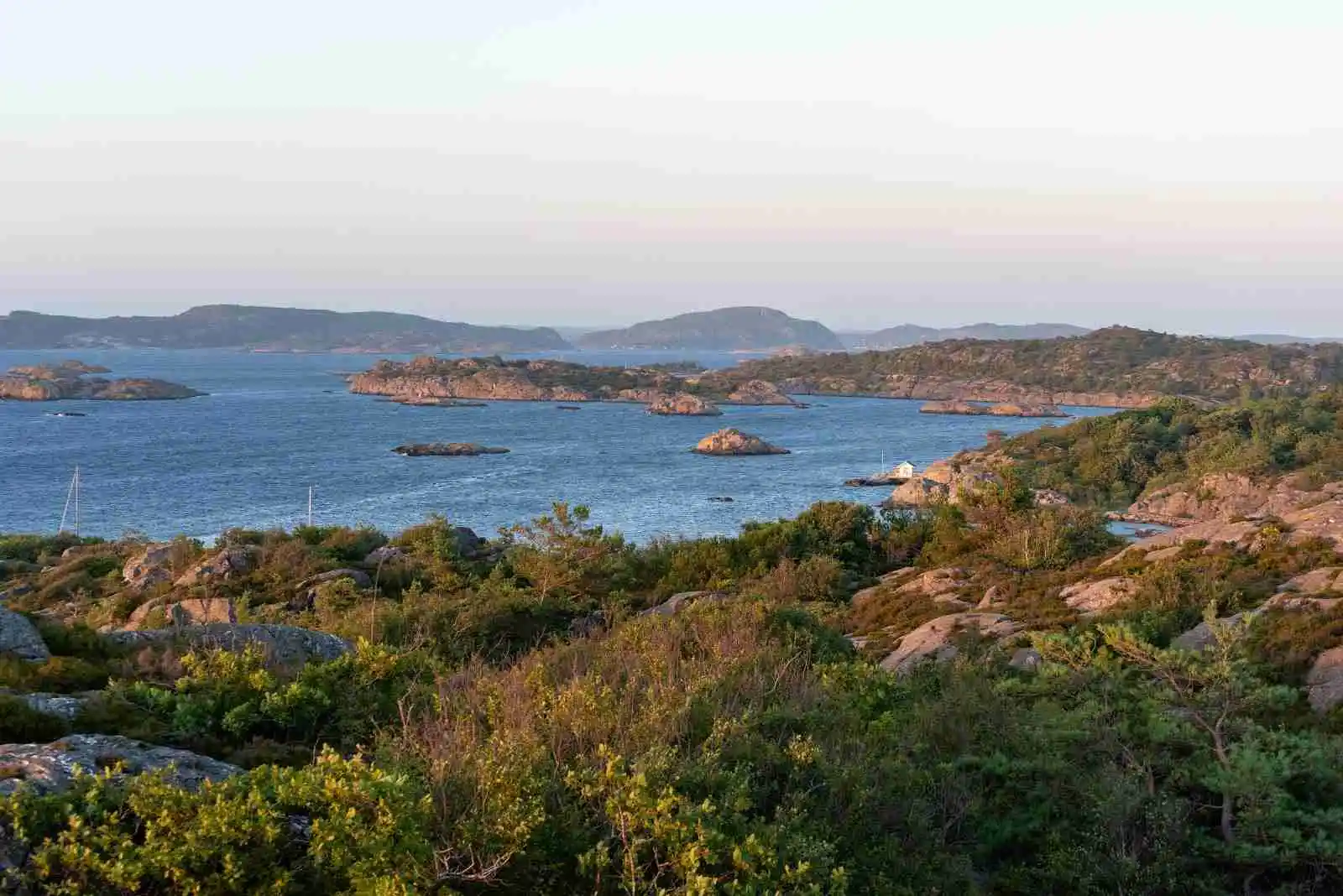 En vy över Marstrands familjecamping med en kustlinje som sträcker sig längs horisonten. Bilden visar vatten i förgrunden, omgiven av klippor och hav, medan den naturliga landskapets skönhet breder ut sig vid kusten.
