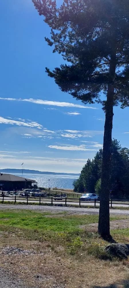 Vy av en somrig kustlandskap vid Gullviks havsbad camping & stugby med blå himmel, moln och vidsträckt horisont över havet.