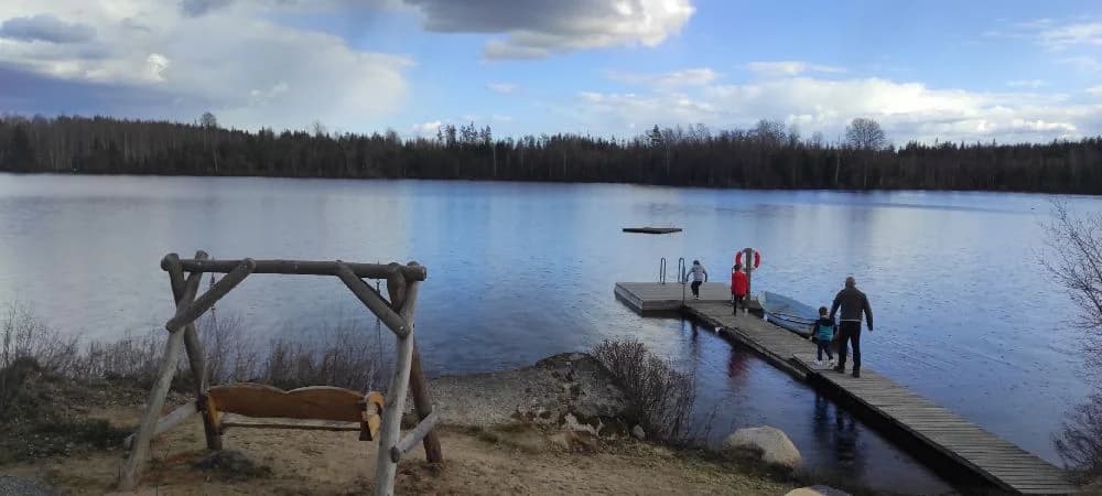 En lugn sjö med brygga och omgivande grönska, vid Abrahams Camp.
