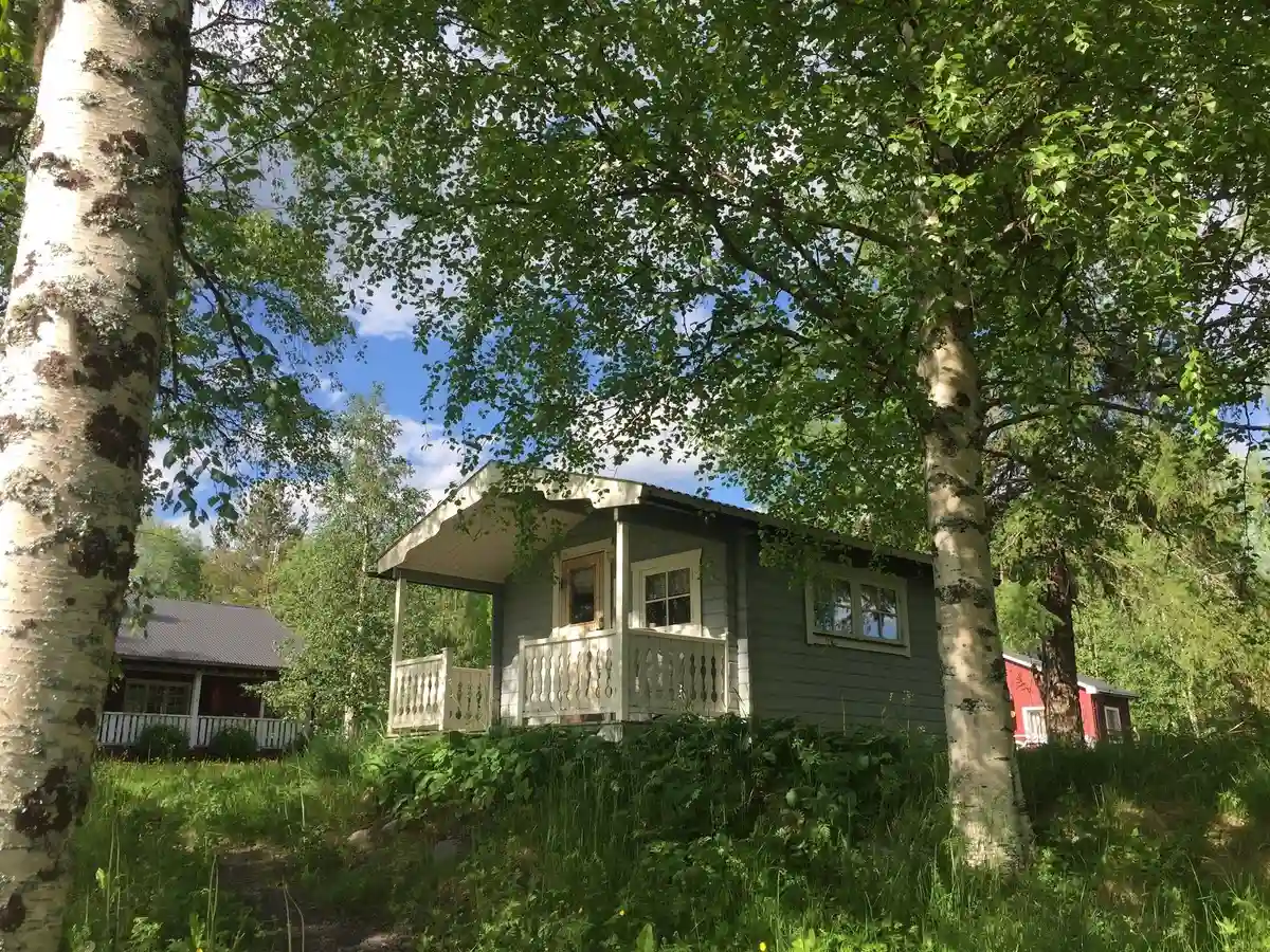 En mysig stuga omgiven av frodig grönska och träd, belägen vid Norråkers camping i en lantlig och avskild miljö.