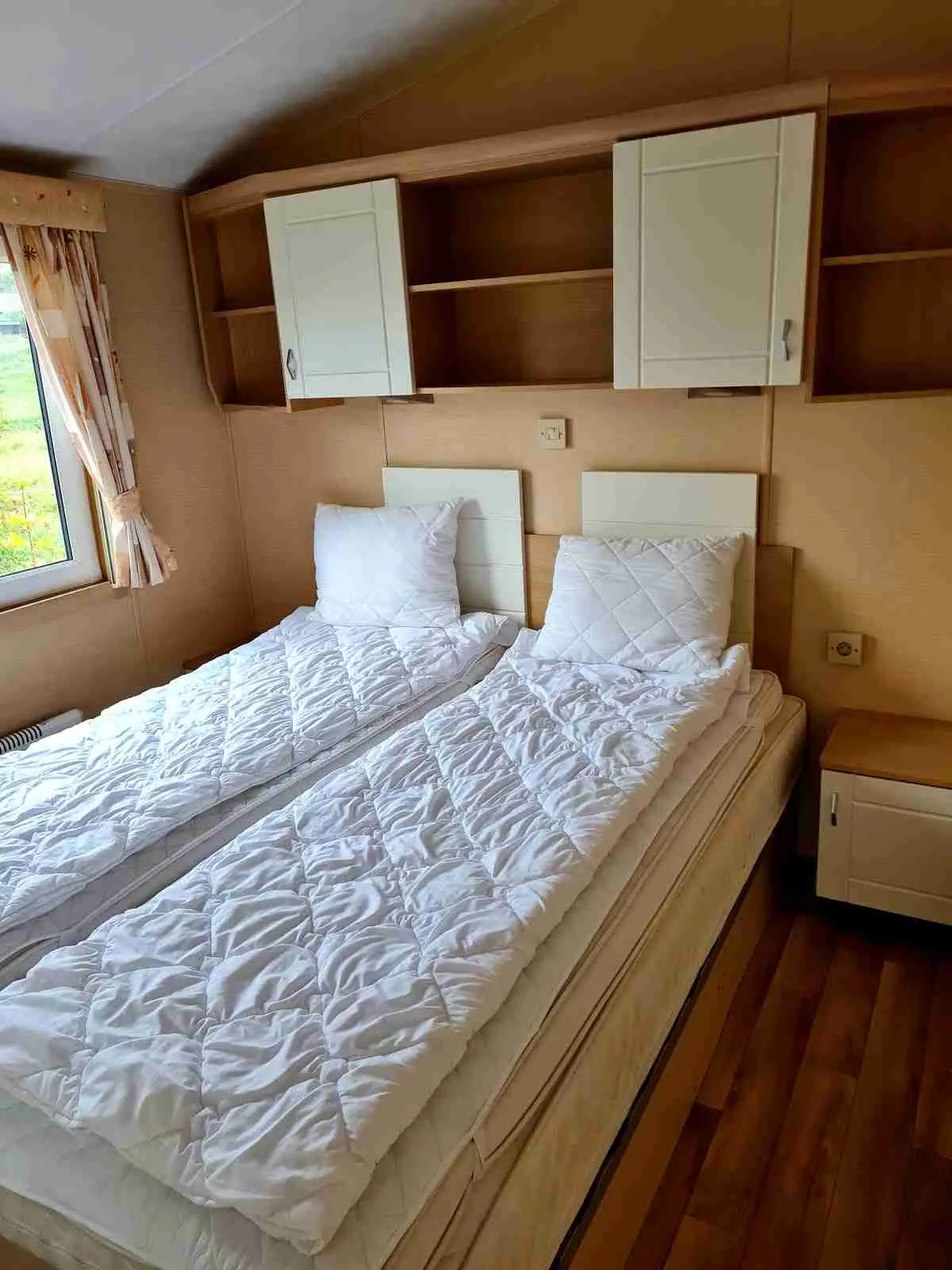 En hemtrevlig sovrumsmiljö med en dubbelsäng bäddad med vita lakan i ett rum med träinredning, inklusive trägolv och väggar.