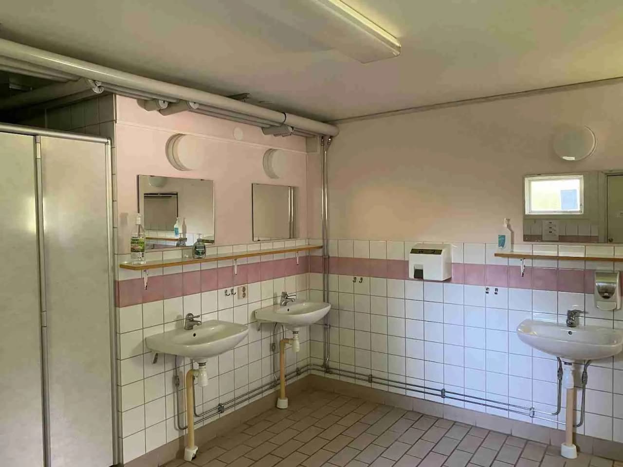 En modern toalett med ett tvättställ, kran och klinkergolv på Luhrsjöbadens camping.