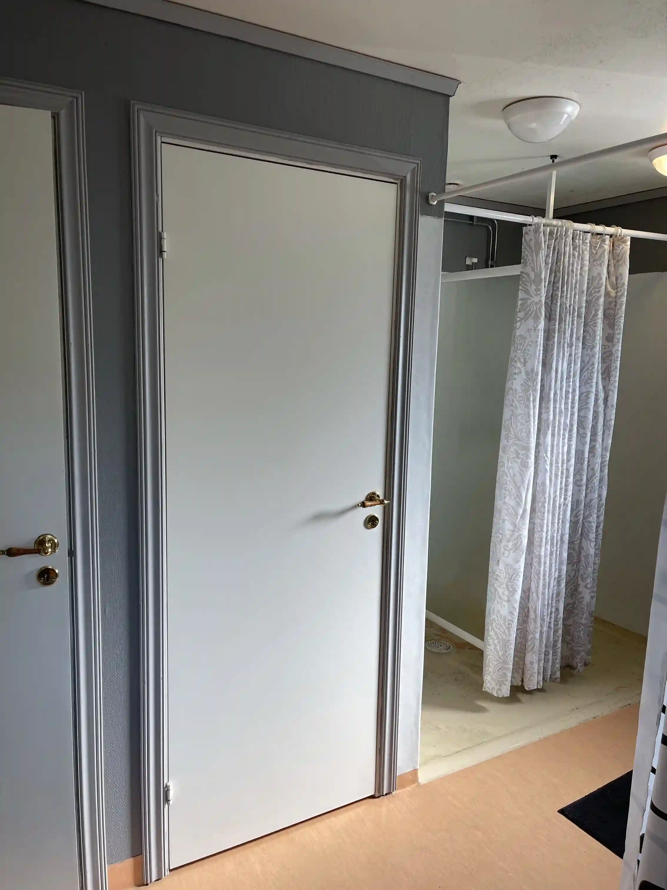 En närbild av en trädörr med metallhandtag, omgiven av ljusa trägolv och lister, som ger en modern och inbjudande känsla.