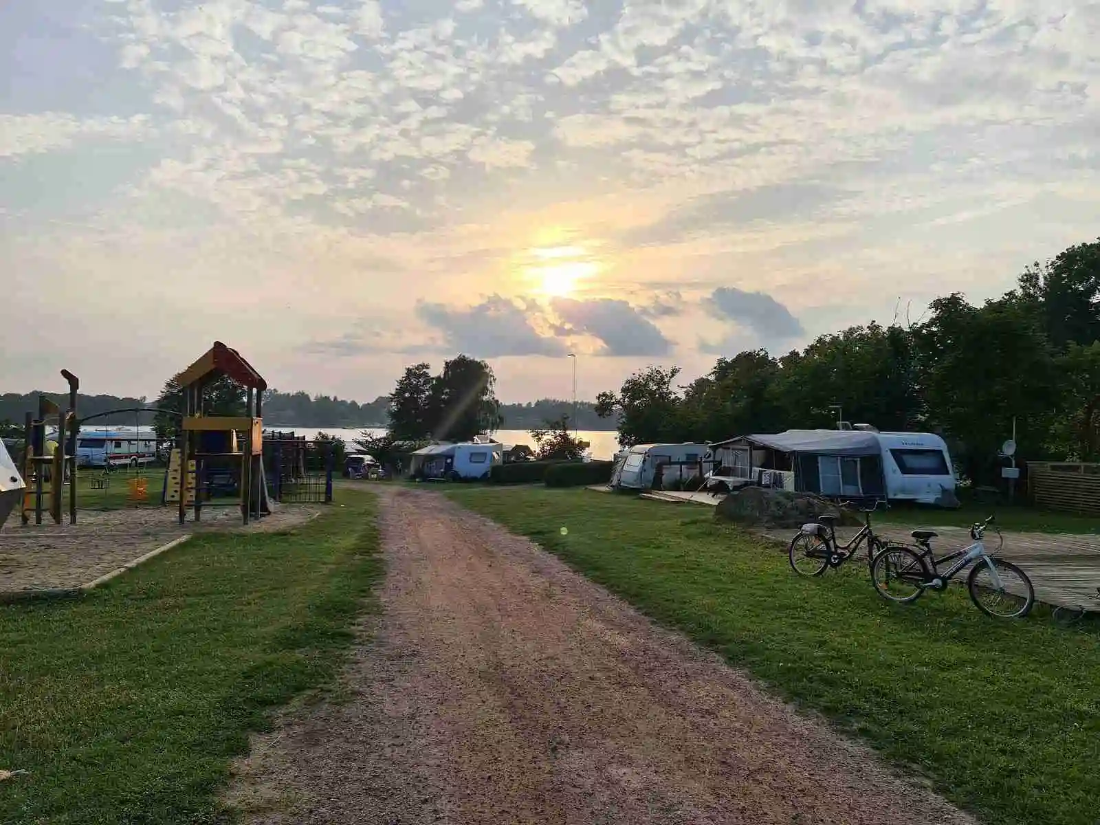 En campingplats med flera parkerade husbilar och familjebilar under en molnig himmel.