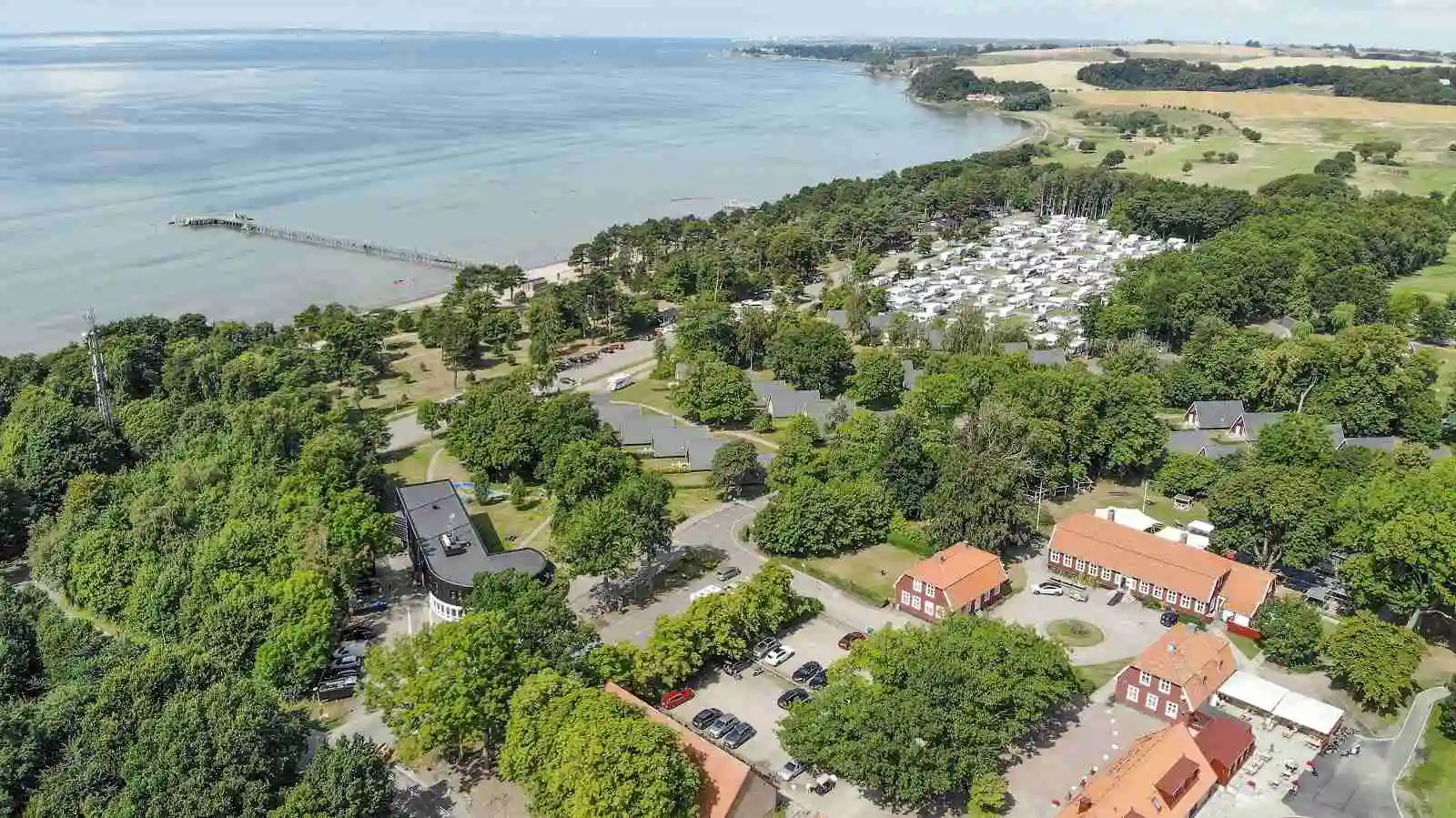Flygbild över Mötesplats Borstahusen med en kustlinje som sträcker sig längs havet. landskapet visar en blandning av strand och grönska, med havet som breder ut sig mot horisonten.