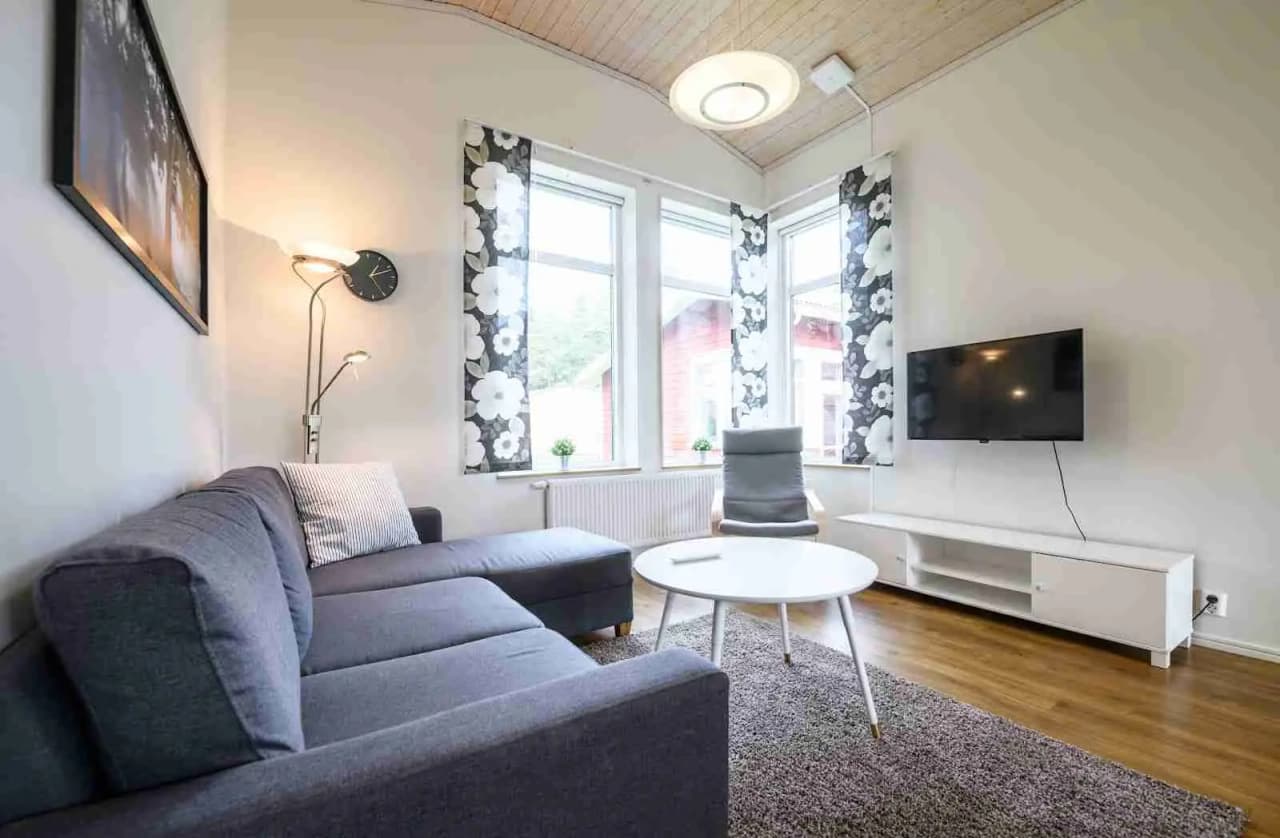 En modern och stilren stuga på Östersunds camping, med ljusa träväggar, bekväm soffa och stora fönster som släpper in naturligt ljus.