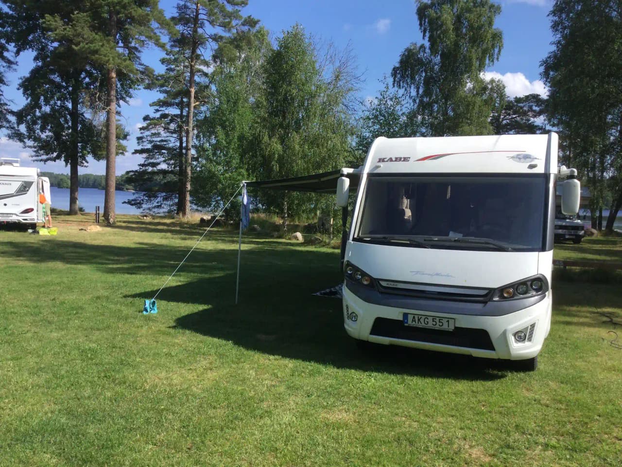 En husbil och en husvagn parkerade på en campingplats omgiven av grönska på Orrefors Camping.