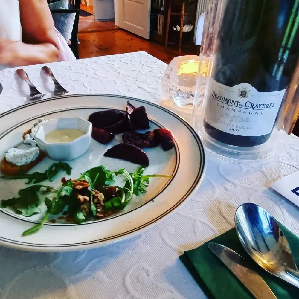 Ett dukat bord med vin- och vattenglas, tallrikar och serveringsfat, redo för en måltid på Kungsgården Långvind.