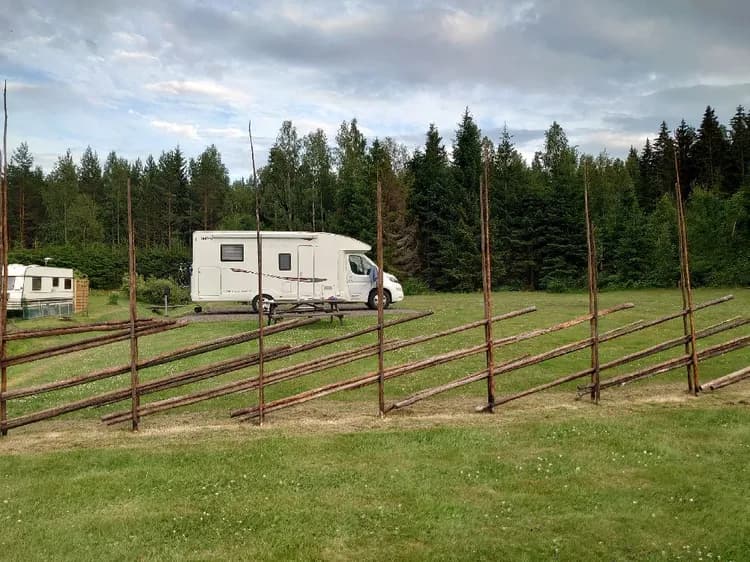 En grönskande campingplats med öppna fält, omgivet av ängar och barrträd, på Svennevads camping.