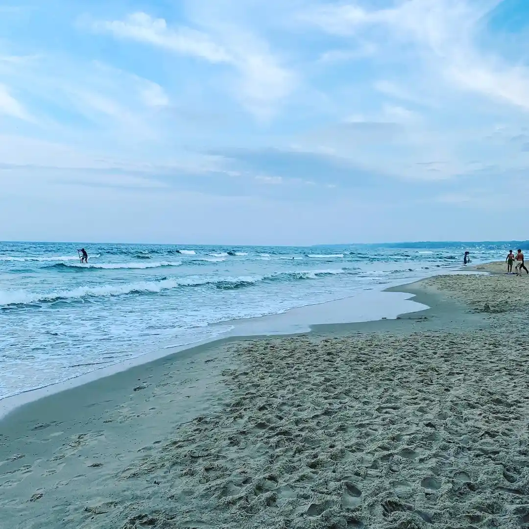 En klarblå himmel sträcker sig över en sandstrand vid havet på ängdala camping, österlen. I horisonten smälter himlen samman med det stilla vattnet, vilket skapar en rogivande och naturskön utsikt.