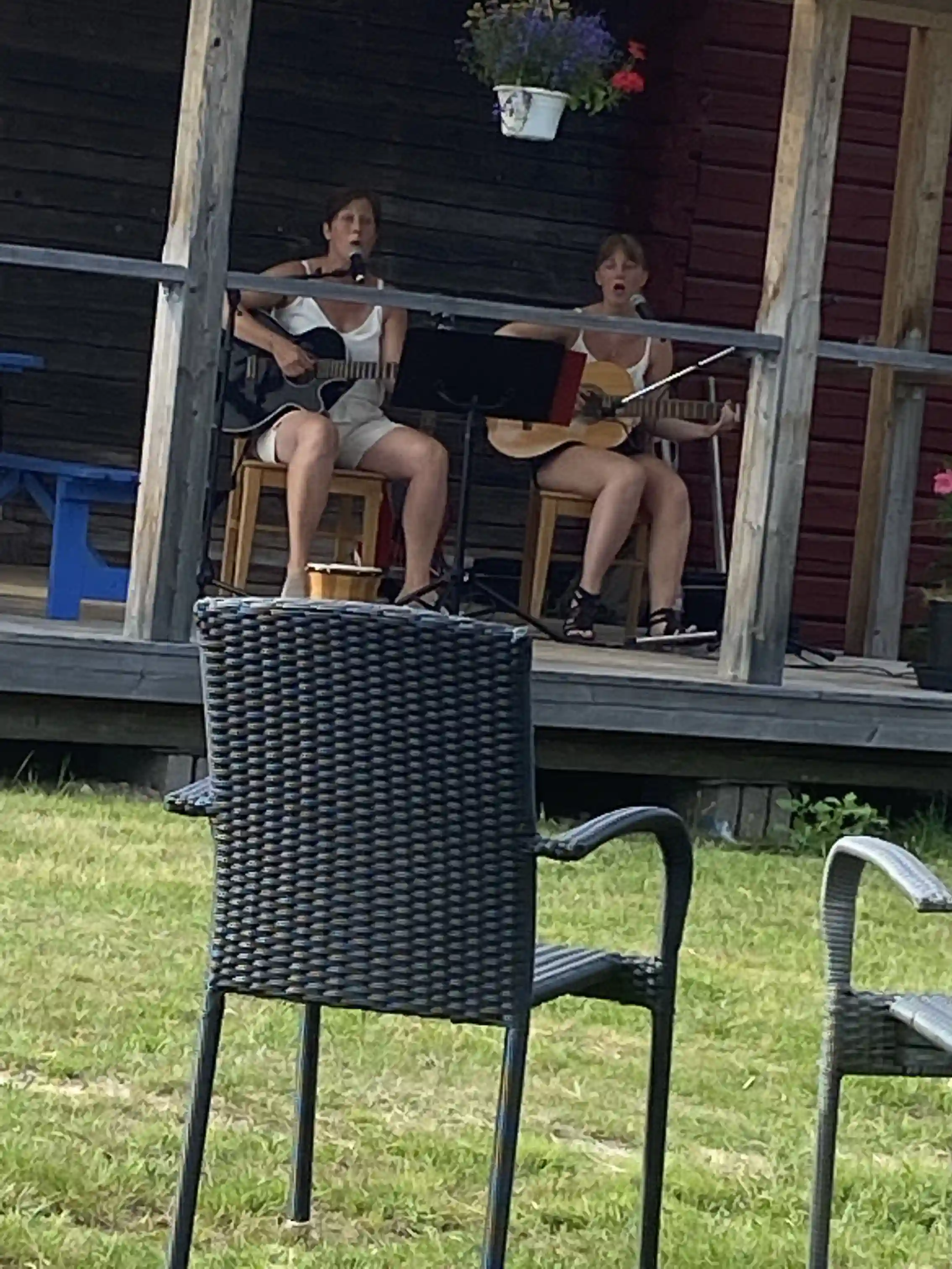 En grupp människor som kopplar av i utomhusmöbler på Värnäs camping en solig sommardag. De sitter och pratar och njuter av fritiden.