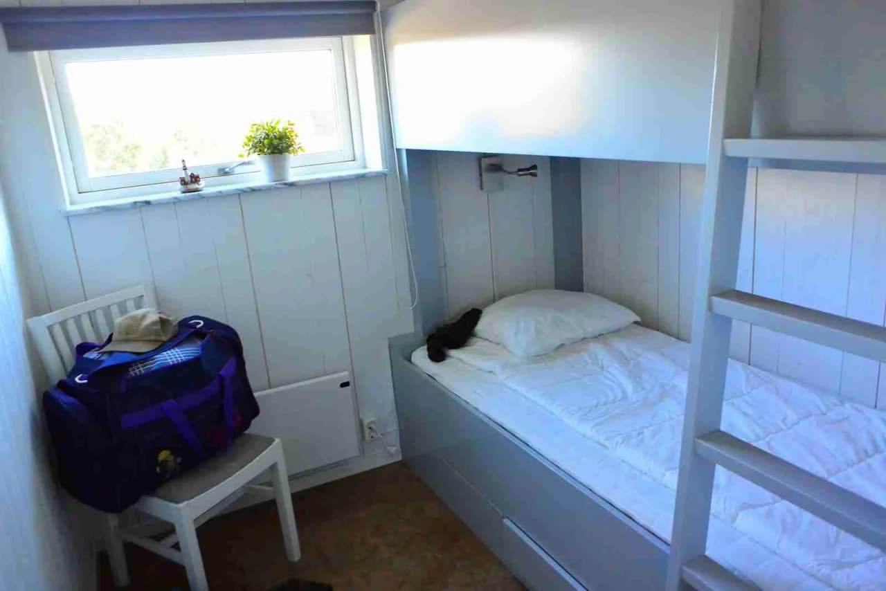 En ljus och inbjudande sovplats med träinredning visar en våningssäng, trägolv och enkel dekor, hos Hav & Logi Skärhamn.