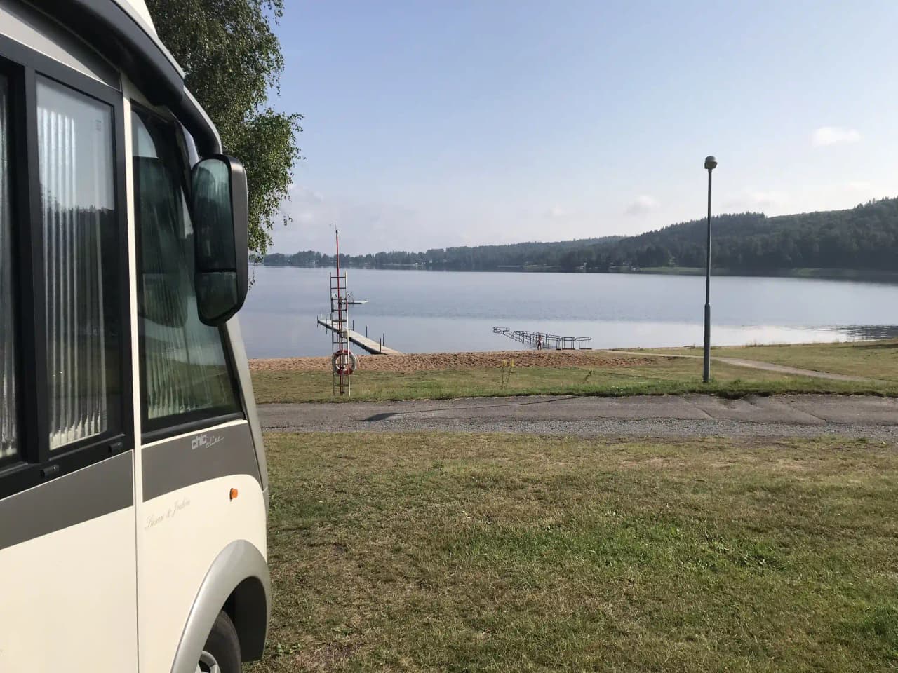 En husbil parkerad på Degernäs camping, omgiven av grönska och skog.