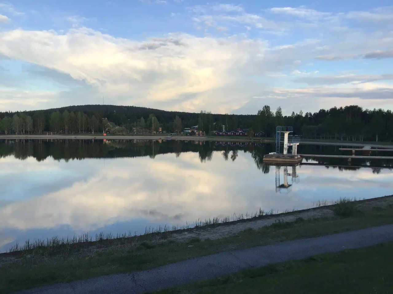 En naturskön vy av en sjö vid Storumans camping, med spegelblanka vattenytor och omgivande grönska.