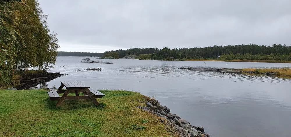 En vacker vy över Sikeå Havscamping med ett stilla vattendrag omgivet av grönskande växtlighet och naturlandskap.