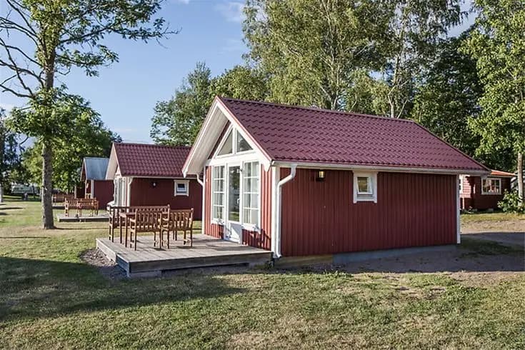 En mysig stuga på Askeviks Camping & Stugor omgiven av lummiga träd och en välskött gård. Stugan har traditionell trädesign och ger en inbjudande och avkopplande atmosfär i naturskön miljö.