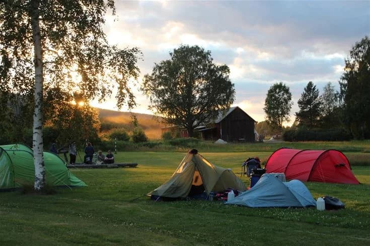 En campingplats vid Björkebo med tält uppsatta på en grönskande äng, omgiven av sommarlandskap och fri himmel, där besökare kan njuta av friluftsliv och rekreation.