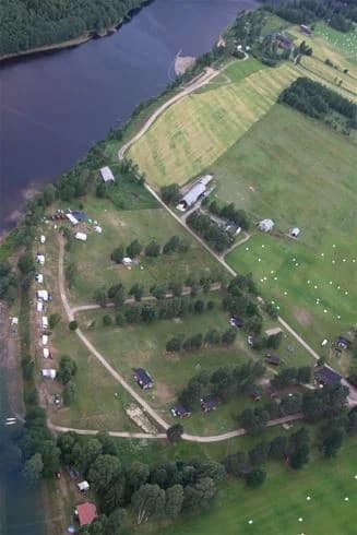 Fågelperspektiv över Björkebo Camping med gröna gräsytor och omgivande landskap i bakgrunden.