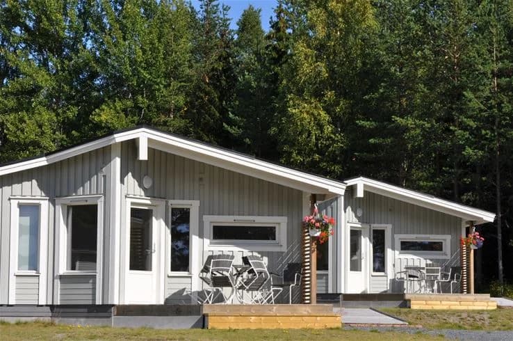 En mysig stugby med traditionella trästugor, omgivna av grönska, som erbjuder ett fridfullt boende nära havet på Gullviks havsbad camping & stugby.