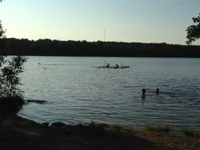 En somrig bild av Långsjön, med en sjö omgiven av grönska och campingmöjligheter. Perfekt för rekreation och friluftsliv.