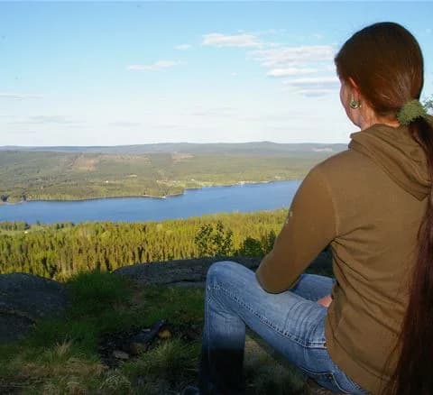 En grupp människor som kopplar av vid en campingplats med utsikt över natursköna höjder och vidsträckt gräslandskap, perfekt för friluftsliv och rekreation.
