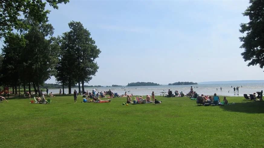 En levande strandscen vid Sikhalls camping med människor som njuter av utomhusaktiviteter och vacker kustmiljö.