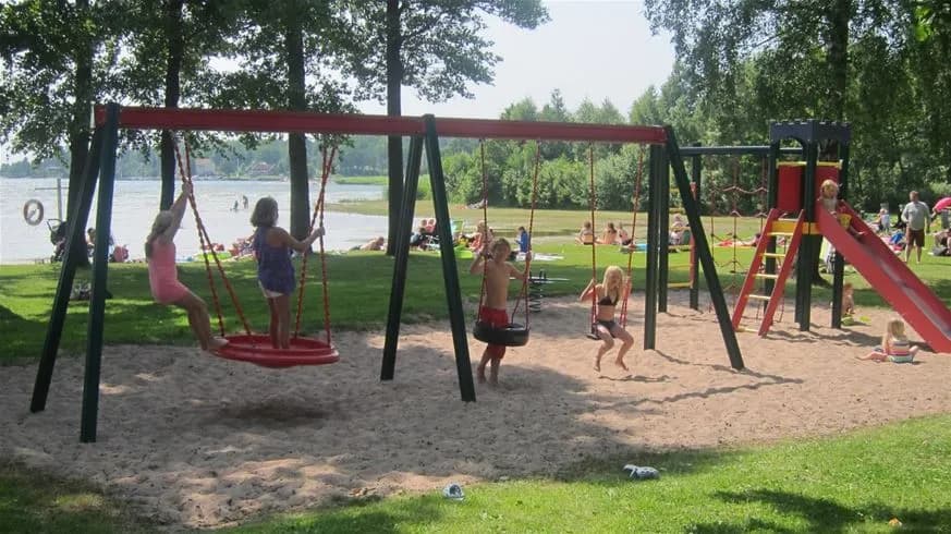 Sikhalls camping lekplats med utomhuslekutrustning och skuggiga områden, en plats för rekreation och nöje i en offentlig miljö.