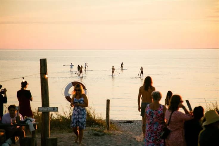 En somrig strand vid horisonten med människor som njuter av semester och fritid i solnedgången vid Tofta Camping.