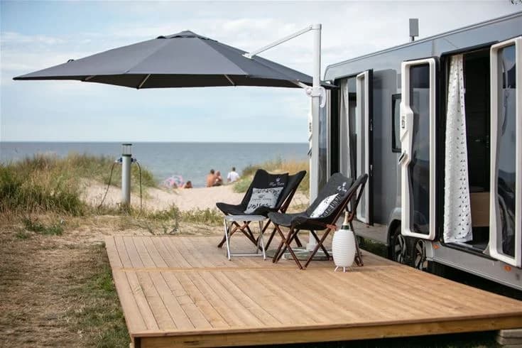 En campingplats med utemöbler i skuggan på en trädeck.