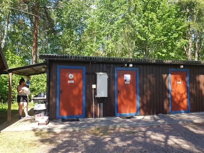 En träbyggnad i skuggan omgiven av grönska på Nås Camping.