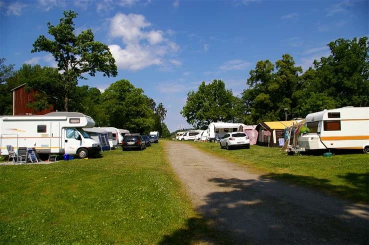 En bild som visar olika husbilar och husvagnar parkerade på Grännäs camping och stugby, omgiven av en lummig parkomgivning.