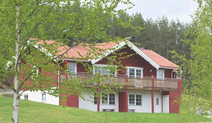 En pittoresk lantlig stuga omgiven av gröna gräsmattor och frodig växtlighet, belägen på Bjursås Berg & Sjö.