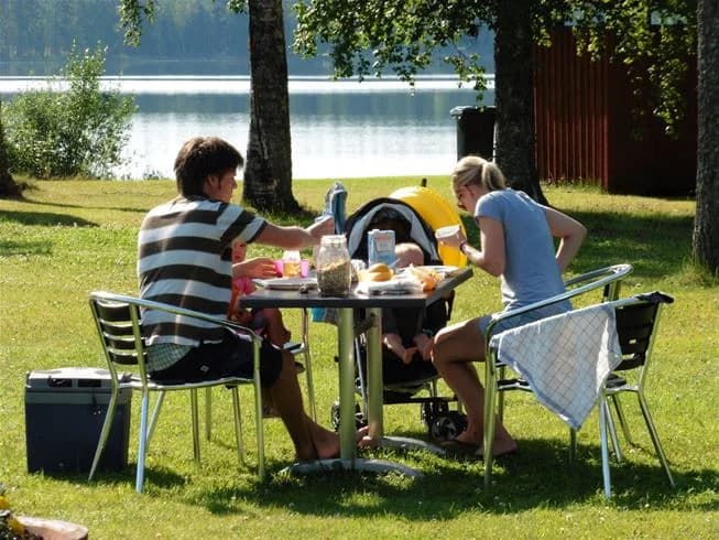 En bild av en möblerad uteplats med stolar och bord, omgiven av grönska, på Bjursås Berg & Sjö, en plats som erbjuder rekreation och fritidsaktiviteter under sommaren.