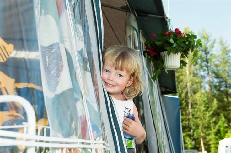 En grupp glada barn leker utomhus på Skellefteå Camping, omgivna av grönska och somrig atmosfär.