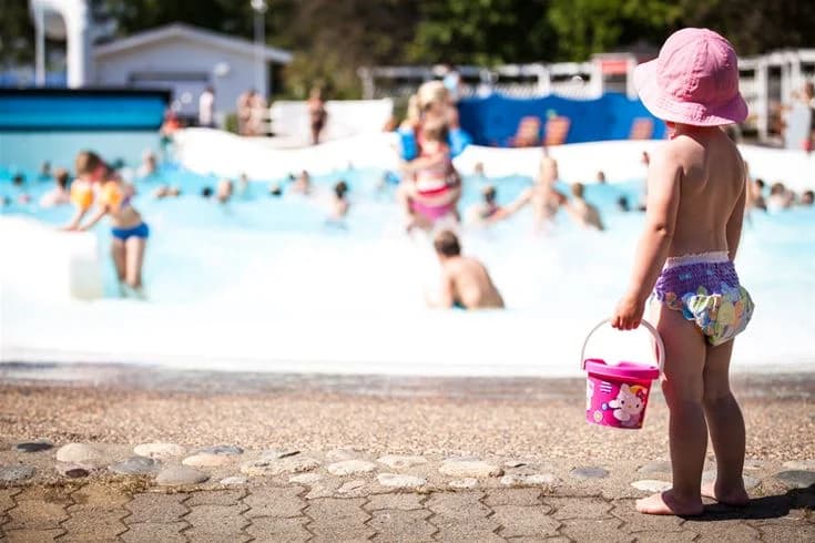 Bild av en vattenpark på Skellefteå Camping med barn som leker i en stor, solbelyst pool. Sommarglädje och rekreation i en familjevänlig miljö.